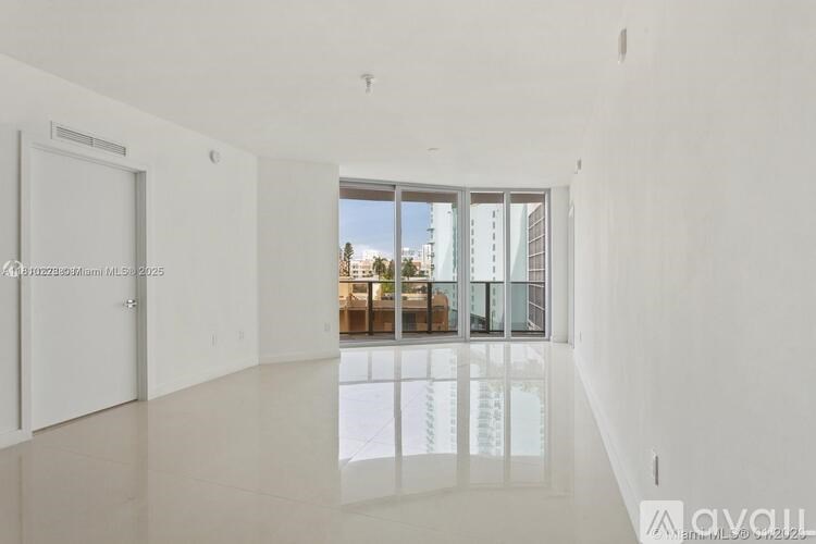 A spacious, empty room with a view of the outside through a large window.