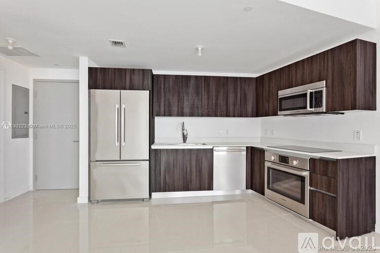 A modern kitchen with dark wood cabinets and stainless steel appliances.