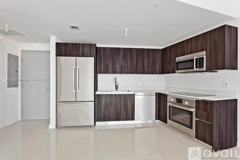 A modern kitchen with dark wood cabinets and stainless steel appliances.