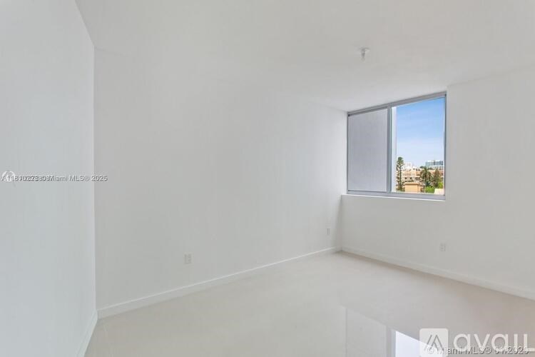 A large empty room with a window overlooking a cityscape.