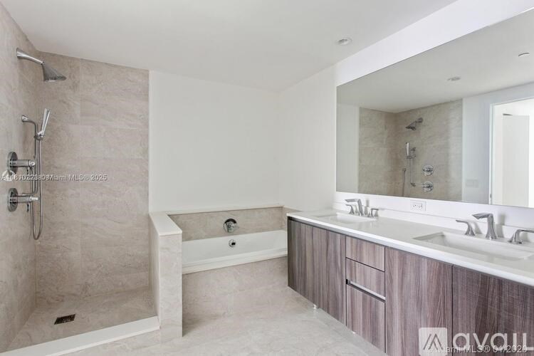 A modern bathroom with a walk-in shower and double sinks.