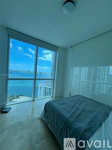 A bedroom with a large bed and a view of the ocean through the window.