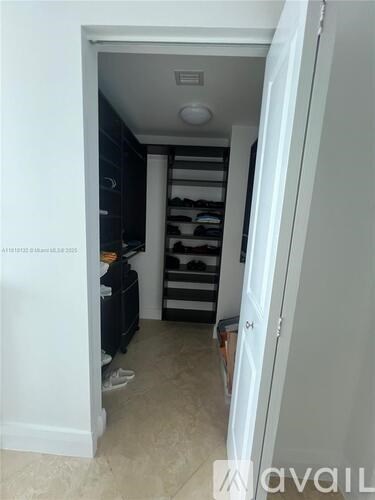 A hallway with a white door and a black shelving unit.