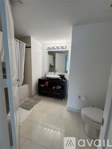 A bathroom with a toilet, sink, and mirror.