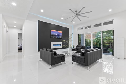 A modern living room with a television and two black sofas.