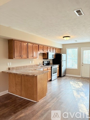 A kitchen with wooden cabinets and a black refrigerator.