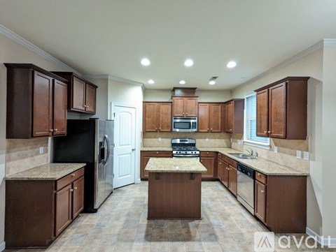 A kitchen with brown cabinets and a black refrigerator.