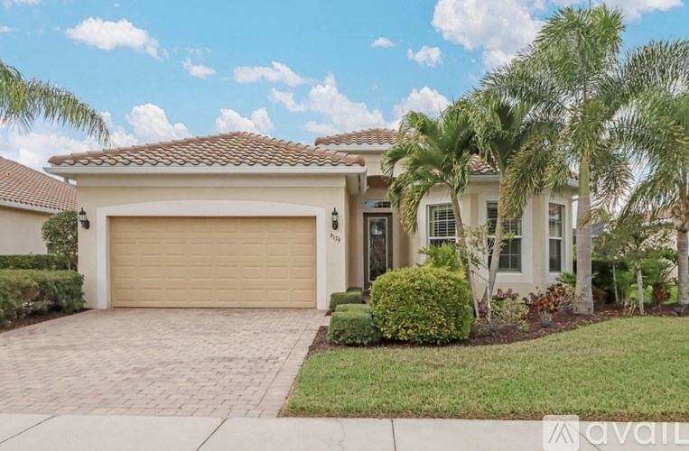 A house with a garage and palm trees in front.