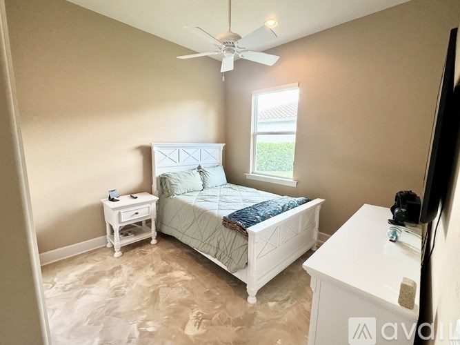 A bedroom with a bed, nightstand, and a fan.