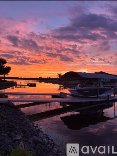 A boat is docked at a pier with a sunset in the background.