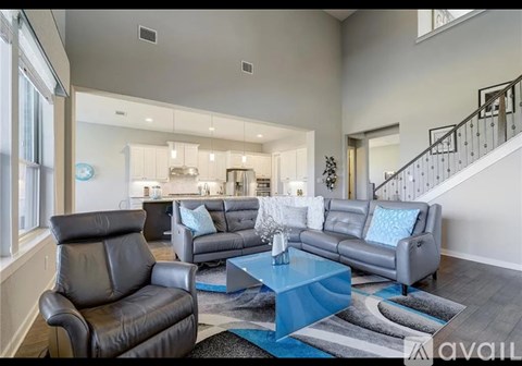 A living room with a black leather couch, a grey couch, and a blue coffee table.