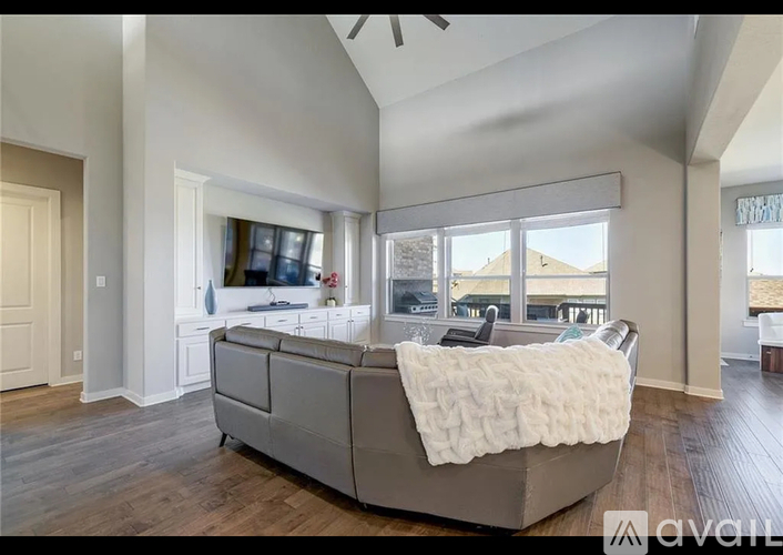 A large, modern bedroom with a bed covered in a white blanket.