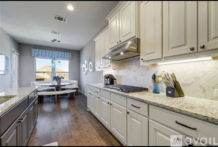 A kitchen with white cabinets and a marble countertop.
