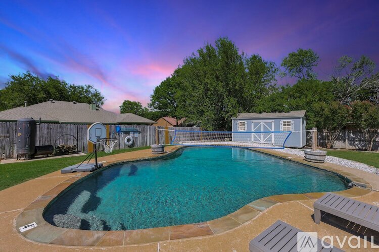 A pool with a basketball hoop and a house in the background.