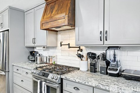 A kitchen with a stove top and a refrigerator.