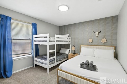 A bedroom with a white bed and bunk beds.