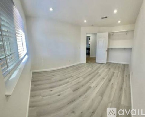 A spacious room with wooden flooring and white walls.