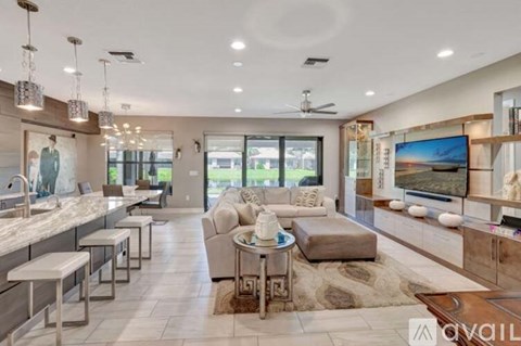 A spacious living room with a kitchen area and a television.