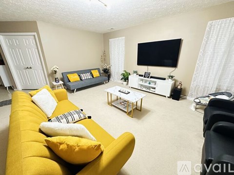 A living room with a yellow sofa and a flat screen TV.