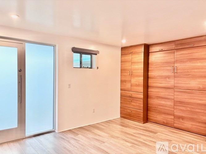 A room with wooden cabinets and a window with blinds.