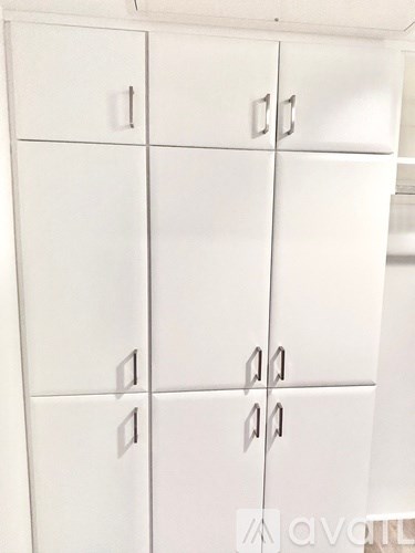 A white cabinet with six doors and four handles.