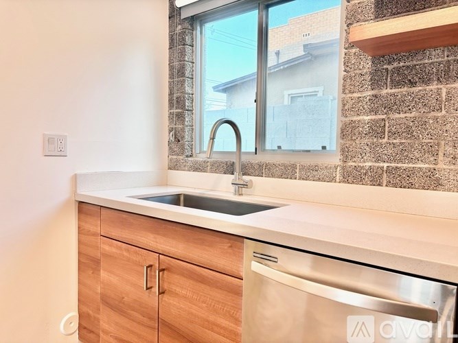 A kitchen with a window, sink, and wooden cabinets.