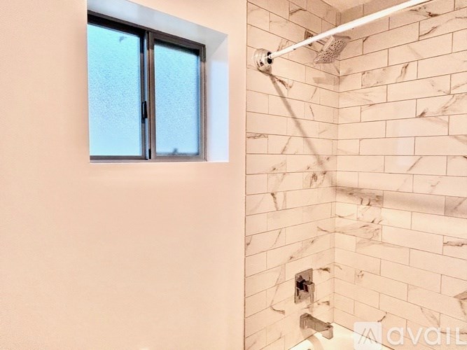 A shower area with a glass door and a tiled wall.