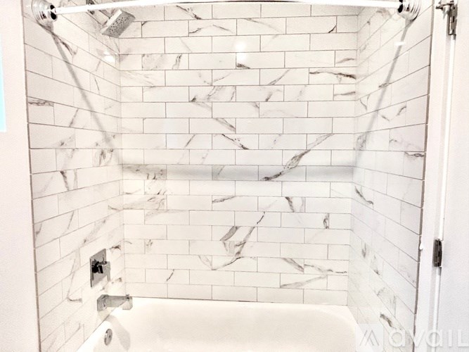 A white tiled bathroom with a white tub.