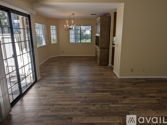 A spacious room with wooden flooring and a chandelier.
