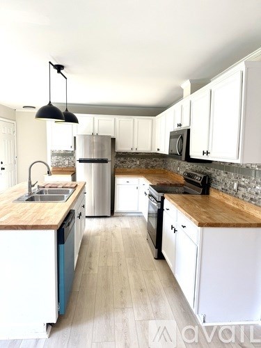 A kitchen with white cabinets and a wooden countertop.