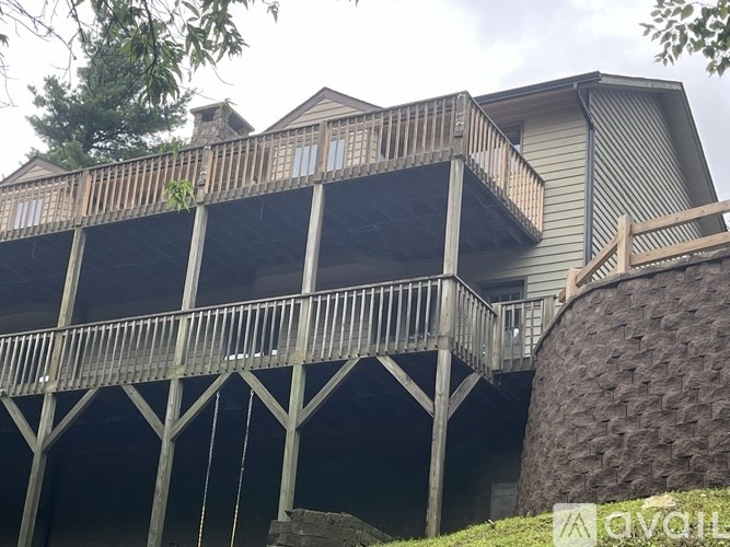 A wooden deck with a metal railing is attached to a house.