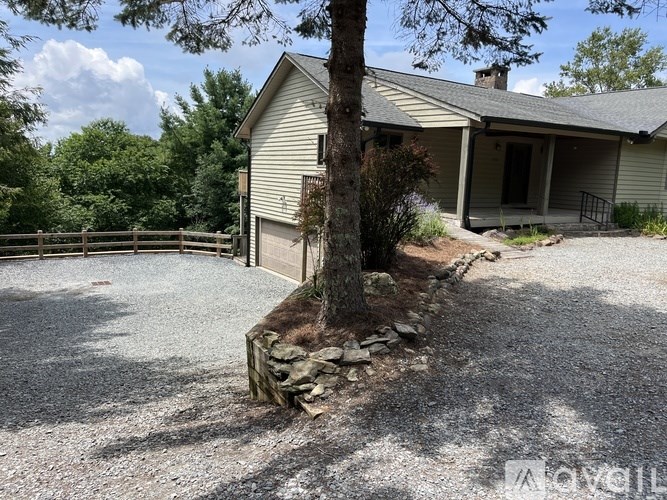 A house with a gravel driveway and a tree in front.