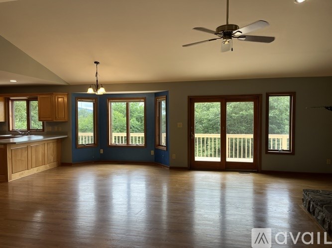 A spacious room with a ceiling fan and large windows.