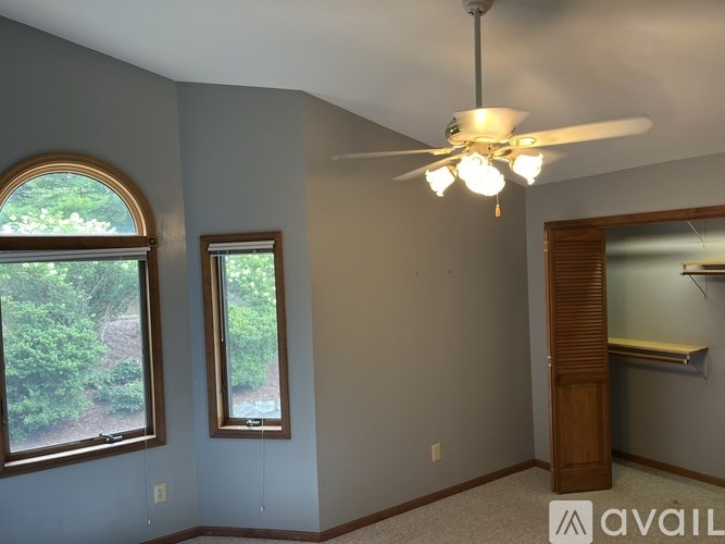 A room with a ceiling fan and two windows.