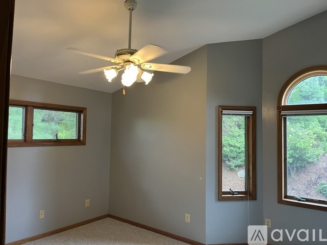 A room with a ceiling fan and two windows.