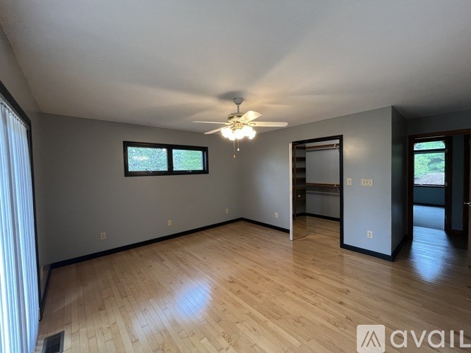 A spacious room with wooden flooring and a ceiling fan.