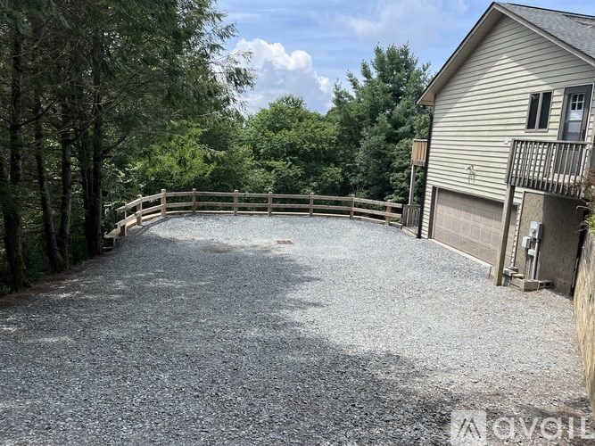 A gravel driveway leads to a house with a deck.