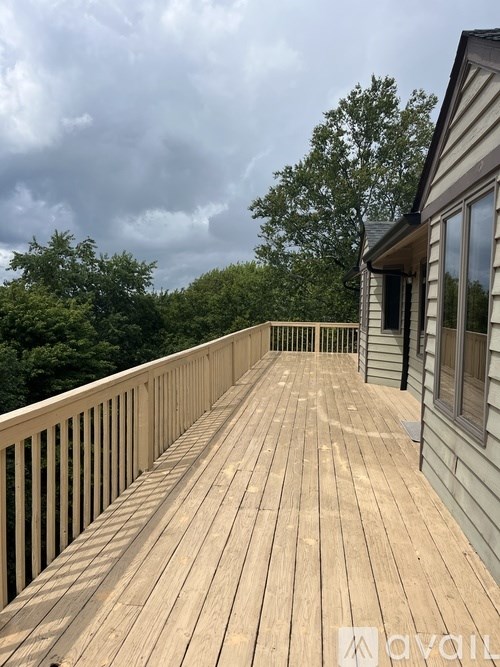 A wooden deck with a railing and a house in the background.