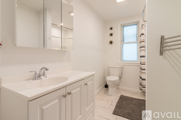 A bathroom with a toilet, sink, and mirror.