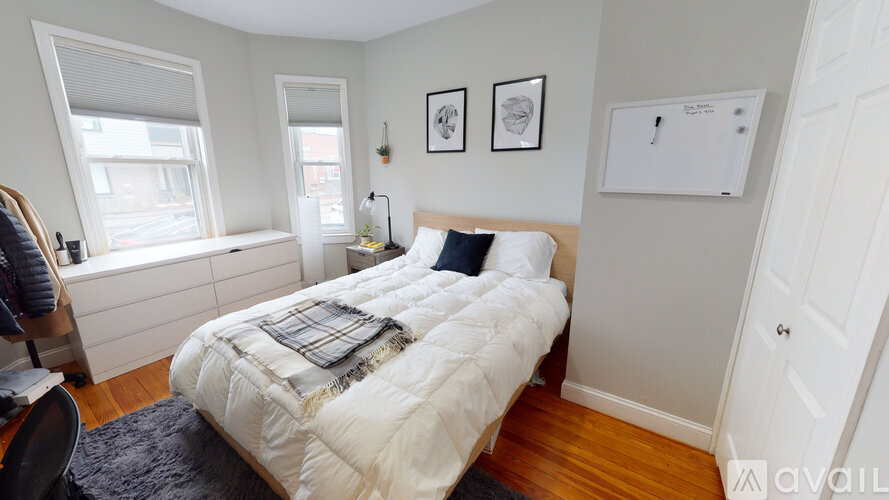 A bedroom with a large bed and a window with blinds.
