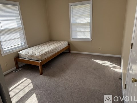 A bedroom with a bed and a carpeted floor.