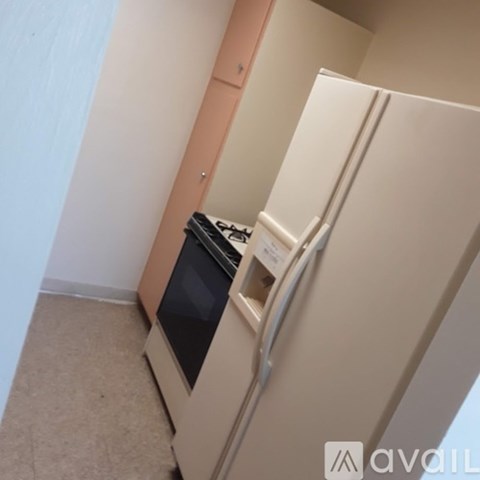 A white refrigerator with a black ice maker drawer in a kitchen.