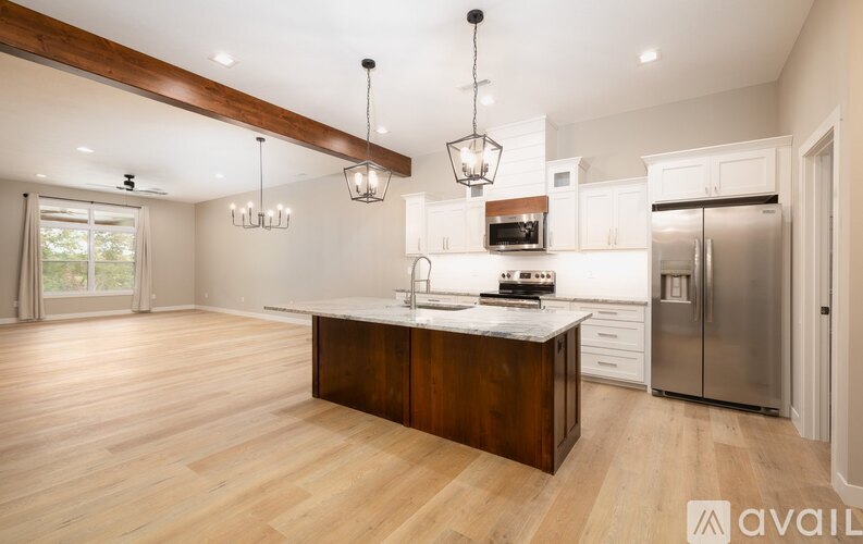 A modern kitchen with wooden floors and stainless steel appliances.