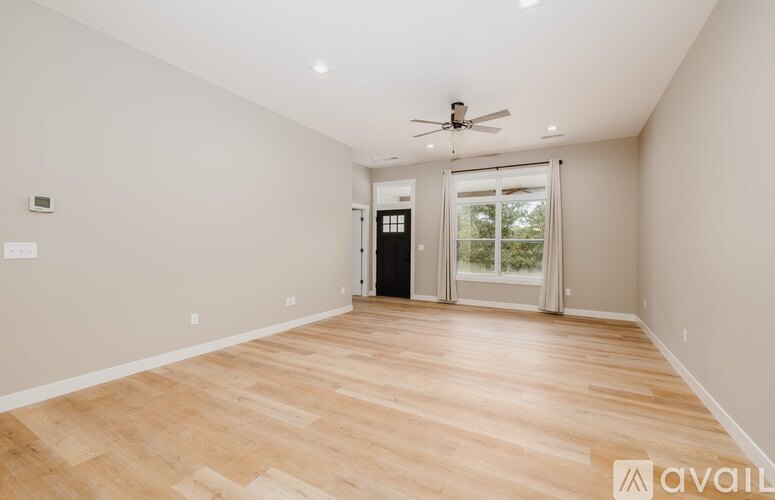 A spacious room with wooden flooring and a ceiling fan.