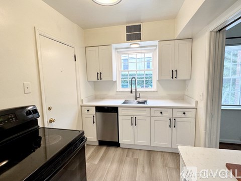 A kitchen with white cabinets and a black stove top oven.