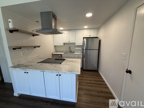 A kitchen with white cabinets and a marble countertop.