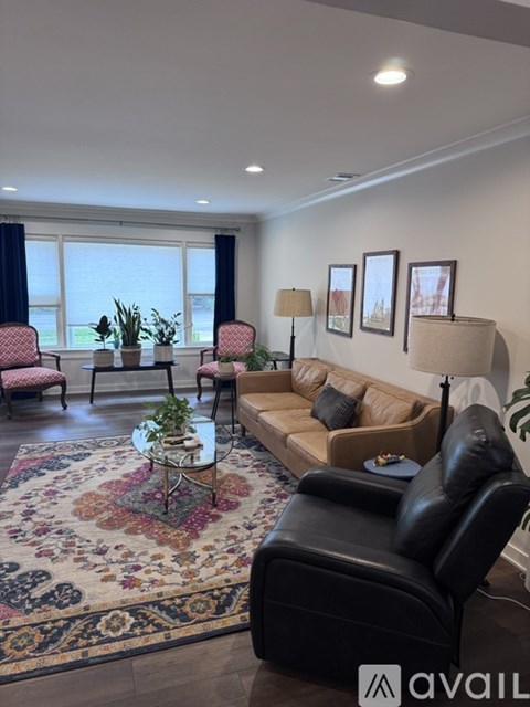 A living room with a rug, a sofa, a chair, and a table with a plant on it.