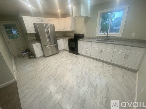 A kitchen with white cabinets and a marble floor.