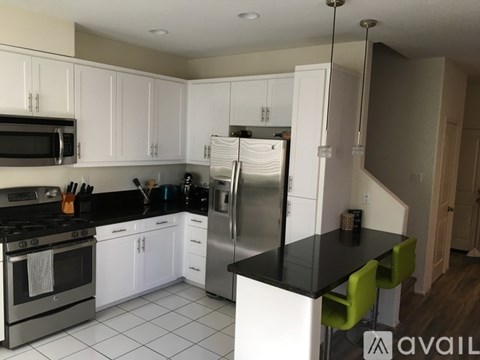 A kitchen with white cabinets and a black countertop.