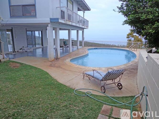 A pool with a hose and a wheelbarrow in the yard of a house.